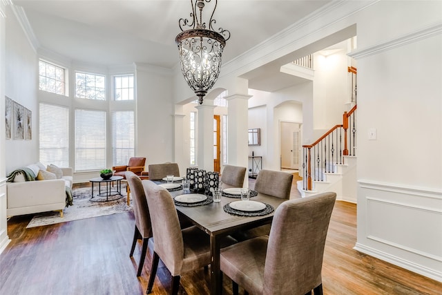 dining room with an inviting chandelier, decorative columns, light hardwood / wood-style flooring, and crown molding