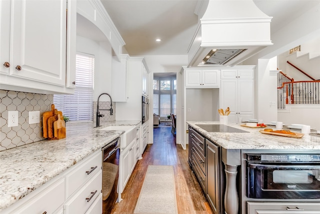 kitchen featuring black appliances, plenty of natural light, light stone counters, and white cabinetry