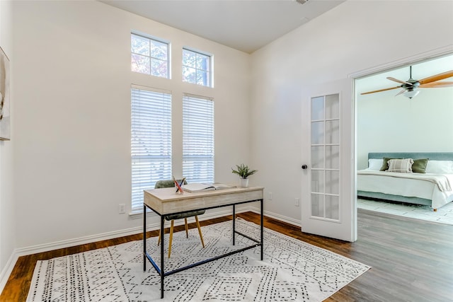 office area featuring ceiling fan, french doors, a towering ceiling, and hardwood / wood-style flooring