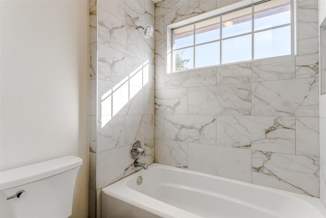 bathroom featuring toilet and tiled shower / bath