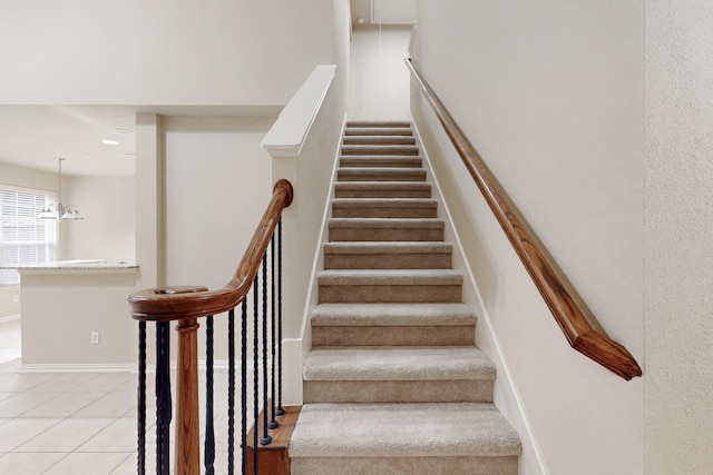 staircase with tile patterned floors and a notable chandelier