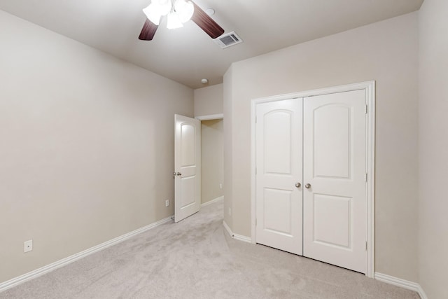 unfurnished bedroom featuring ceiling fan, a closet, and light colored carpet