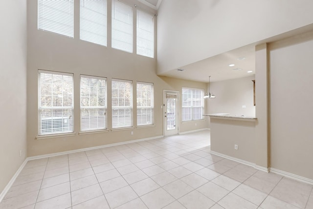 unfurnished living room featuring a healthy amount of sunlight, light tile patterned flooring, and a high ceiling