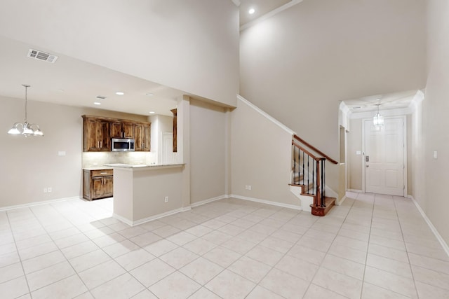 unfurnished living room featuring light tile patterned flooring, a high ceiling, and a chandelier