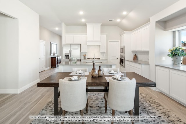 dining space featuring light hardwood / wood-style flooring, lofted ceiling, and sink