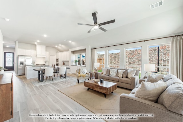 living room featuring vaulted ceiling, light hardwood / wood-style flooring, and ceiling fan