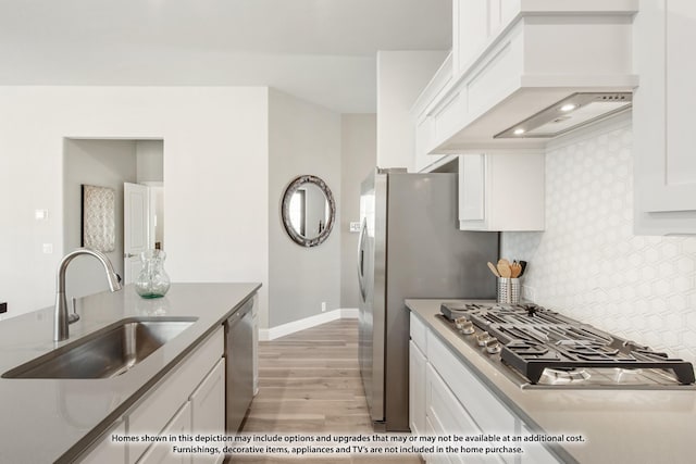 kitchen featuring premium range hood, white cabinets, sink, light wood-type flooring, and stainless steel appliances