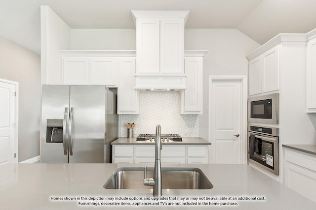 kitchen with white cabinets, backsplash, stainless steel appliances, and vaulted ceiling