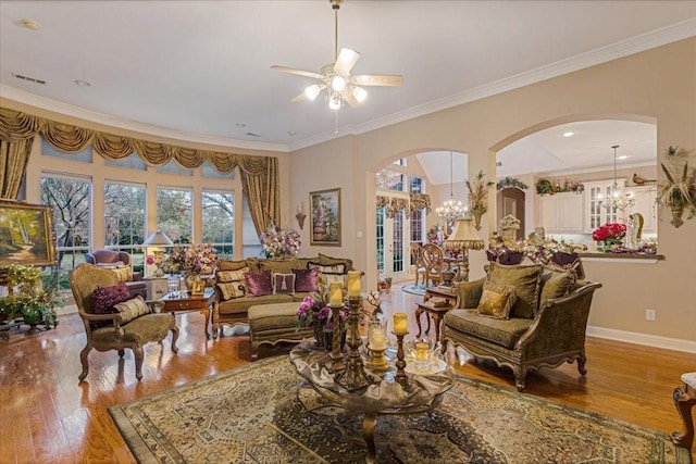 living room with crown molding, ceiling fan with notable chandelier, and light wood-type flooring