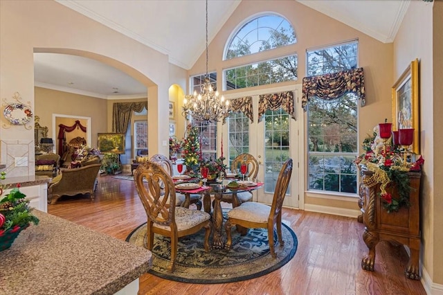 1305 Bentbrook Ln, Sherman, TX 75092 - dining space featuring arched walkways, wood finished floors, a chandelier, high vaulted ceiling, and crown molding
