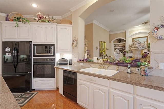 kitchen with black appliances, light hardwood / wood-style floors, white cabinets, and sink