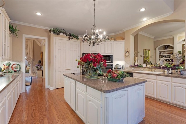 kitchen with sink, white cabinetry, stainless steel microwave, a kitchen island, and pendant lighting