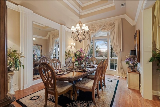 dining space with crown molding, an inviting chandelier, and light wood-type flooring