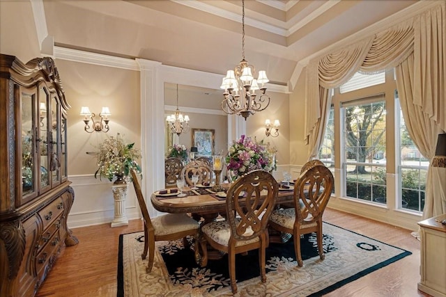 dining room featuring a tray ceiling, crown molding, an inviting chandelier, and light wood-type flooring