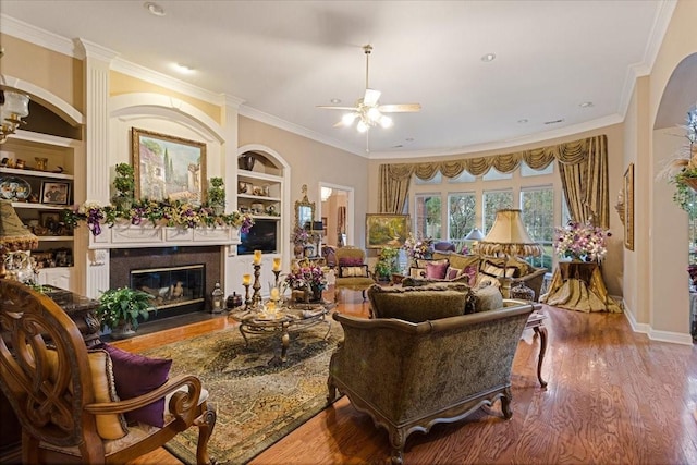 living room with wood-type flooring, ceiling fan, crown molding, and a premium fireplace