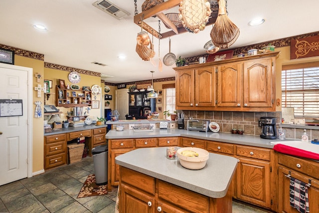 kitchen with backsplash, a wealth of natural light, a kitchen island, and decorative light fixtures