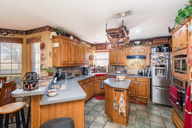 kitchen with a kitchen bar, decorative backsplash, a kitchen island, and appliances with stainless steel finishes