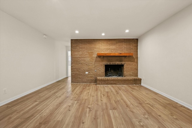 unfurnished living room featuring a fireplace and light hardwood / wood-style floors