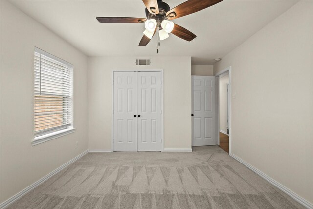 unfurnished bedroom with ceiling fan, a closet, and light carpet