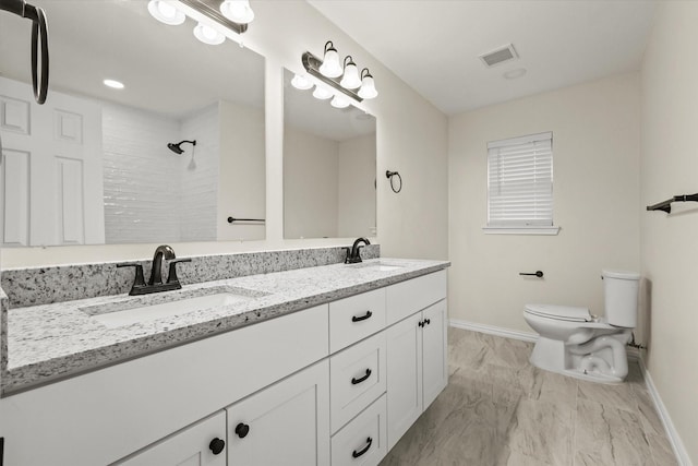 bathroom with tiled shower, vanity, and toilet