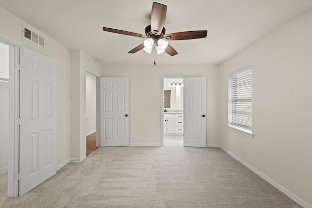 unfurnished bedroom featuring ceiling fan, ensuite bathroom, and light carpet