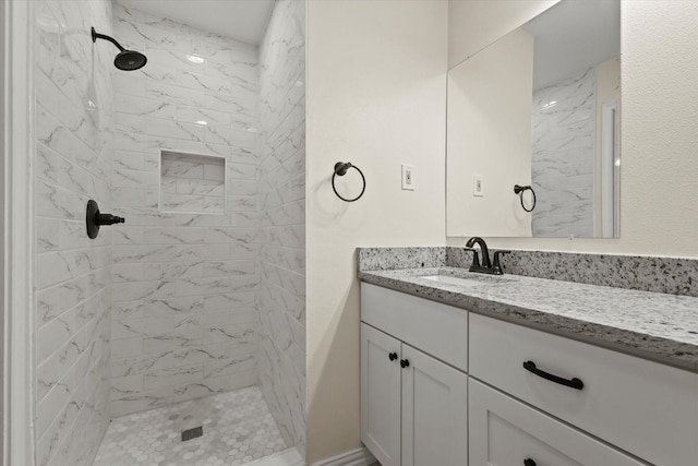 bathroom with tiled shower and vanity