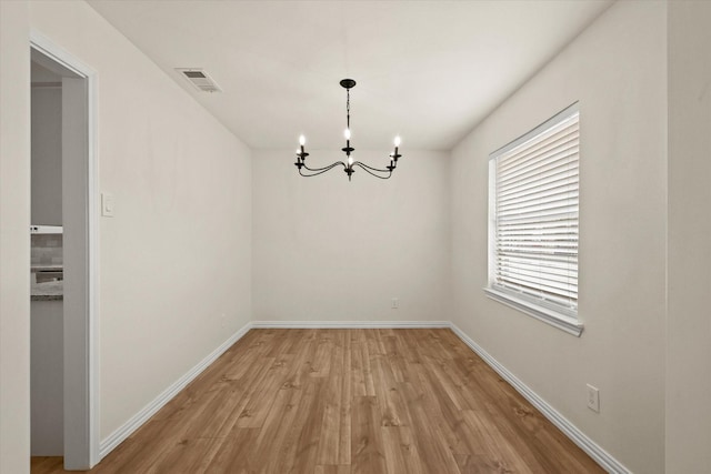 unfurnished dining area with a chandelier and light hardwood / wood-style flooring