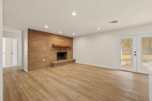 unfurnished living room featuring a fireplace, french doors, and light hardwood / wood-style flooring