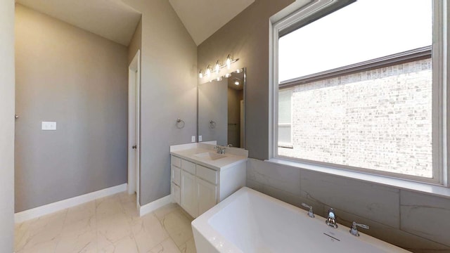 bathroom with vanity, vaulted ceiling, and a bathtub