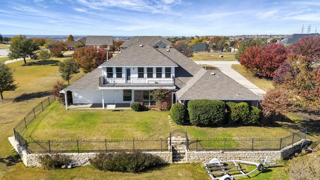 rear view of property featuring a balcony and a yard