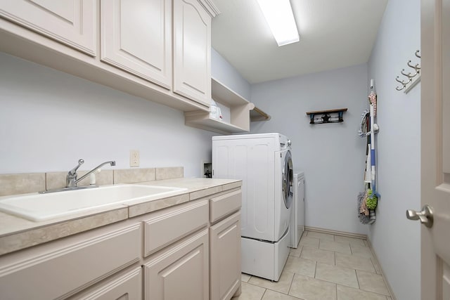 laundry area with sink, light tile patterned floors, washing machine and dryer, and cabinets