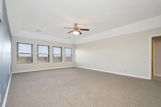 carpeted spare room featuring a tray ceiling and ceiling fan