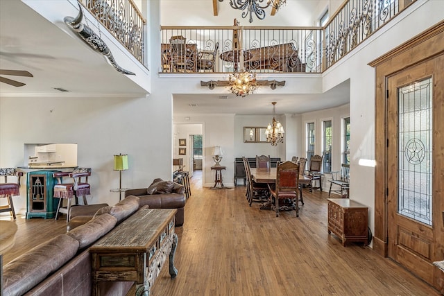 living room with ceiling fan with notable chandelier, a towering ceiling, hardwood / wood-style flooring, and ornamental molding