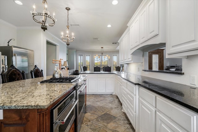 kitchen featuring decorative light fixtures, white cabinetry, high end stove, and kitchen peninsula