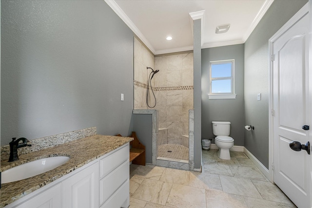 bathroom featuring a tile shower, vanity, toilet, and ornamental molding