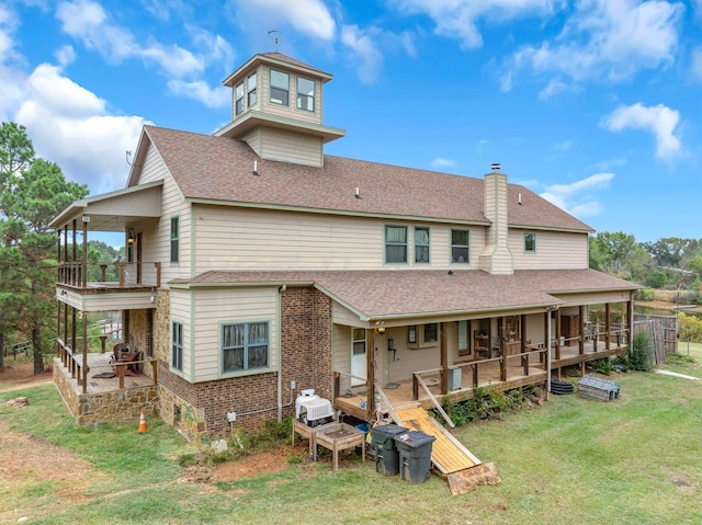 rear view of house featuring a wooden deck and a lawn