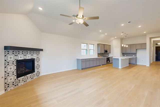 7220 Monarch Trl, Mckinney, TX 75071 - unfurnished living room featuring lofted ceiling, light wood finished floors, ceiling fan, a tiled fireplace, and recessed lighting