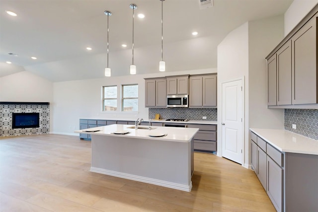 7220 Monarch Trl, Mckinney, TX 75071 - kitchen with gray cabinetry, lofted ceiling, stainless steel microwave, light wood-style floors, and recessed lighting