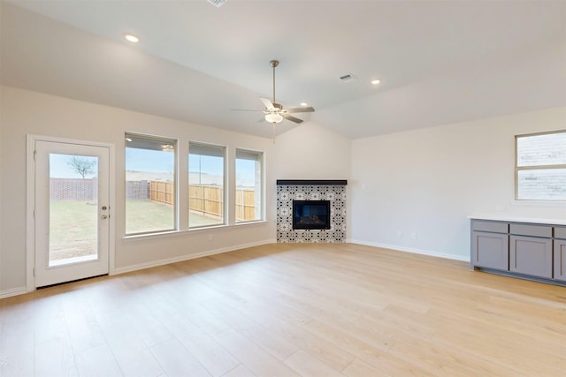7220 Monarch Trl, Mckinney, TX 75071 - unfurnished living room featuring ceiling fan, light wood-style floors, a tiled fireplace, baseboards, and lofted ceiling
