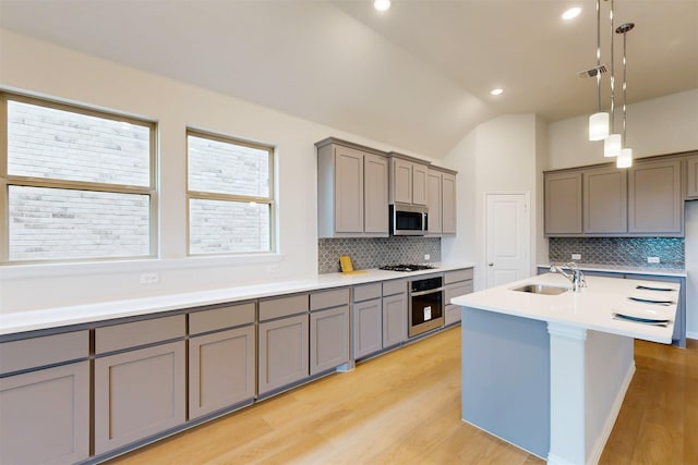 7220 Monarch Trl, Mckinney, TX 75071 - kitchen featuring gray cabinetry, appliances with stainless steel finishes, a sink, light wood-style flooring, and lofted ceiling