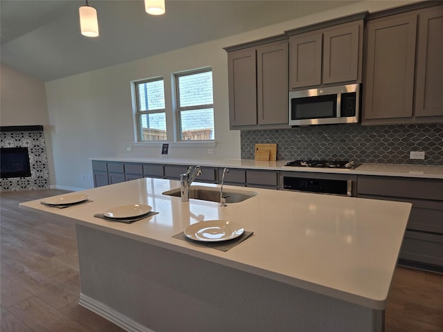 7220 Monarch Trl, Mckinney, TX 75071 - kitchen with gray cabinetry, stainless steel microwave, a sink, dark wood-style flooring, and vaulted ceiling