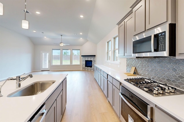 7220 Monarch Trl, Mckinney, TX 75071 - kitchen with appliances with stainless steel finishes, a sink, a tile fireplace, decorative backsplash, and a ceiling fan