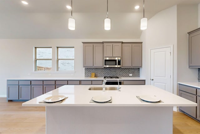 7220 Monarch Trl, Mckinney, TX 75071 - kitchen with stainless steel microwave, gray cabinets, lofted ceiling, decorative backsplash, and light wood finished floors