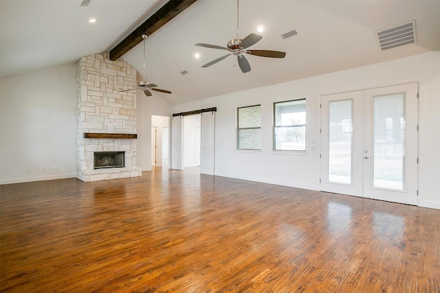 unfurnished living room with ceiling fan, french doors, a barn door, beamed ceiling, and dark hardwood / wood-style floors