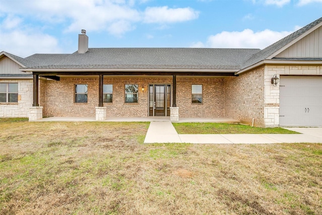 rear view of house featuring a garage, a yard, and covered porch