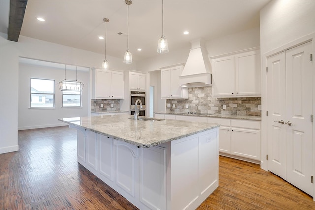 kitchen featuring hardwood / wood-style floors, white cabinetry, and custom range hood