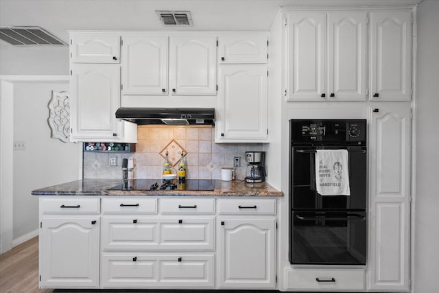 kitchen featuring white cabinetry, extractor fan, light hardwood / wood-style floors, decorative backsplash, and black appliances