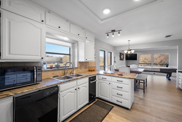 kitchen with dishwasher, kitchen peninsula, light hardwood / wood-style floors, decorative light fixtures, and white cabinets