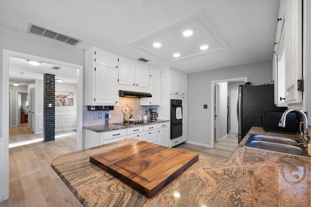 kitchen with sink, white cabinets, extractor fan, and light wood-type flooring