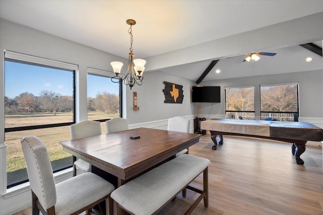 dining area featuring ceiling fan with notable chandelier, a healthy amount of sunlight, lofted ceiling with beams, and light hardwood / wood-style flooring